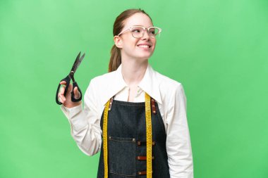 Terzi kadın izole edilmiş krom anahtar arka planda yukarı bakarken bir fikir düşünüyor.