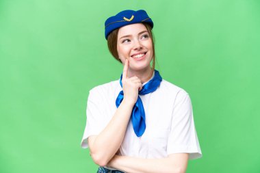 Airplane stewardess over isolated chroma key background thinking an idea while looking up