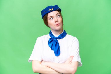 Airplane stewardess over isolated chroma key background making doubts gesture while lifting the shoulders