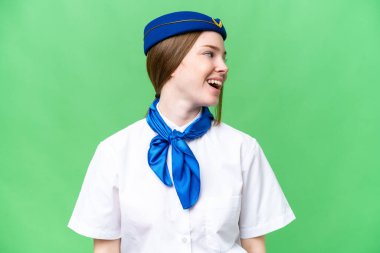 Airplane stewardess over isolated chroma key background laughing in lateral position