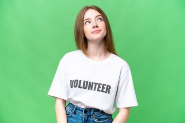Young volunteer woman over isolated chroma key background and looking up
