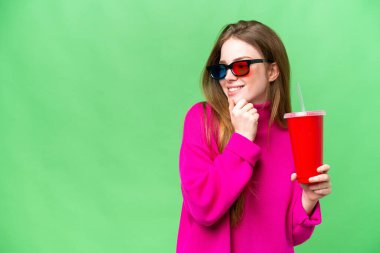 Young woman holding soda while watching a 3D movie thinking an idea and looking side