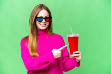 Genç bir kadın elinde soda tutarken 3 boyutlu bir film izliyor ve onu doğrultuyor.