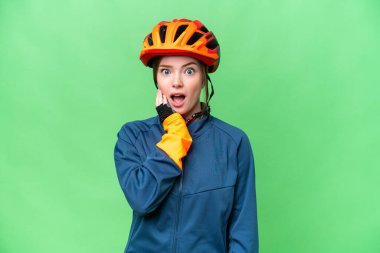 Young cyclist woman over isolated chroma key background surprised and shocked while looking right