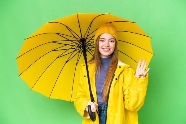 Young pretty woman with rainproof coat and umbrella over isolated chroma key background happy and counting four with fingers