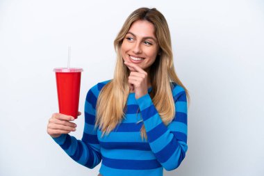 Young Uruguayan woman drinking soda isolated on white background looking to the side and smiling