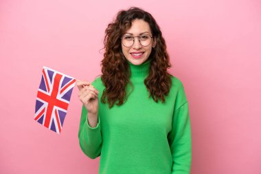 Young caucasian woman holding English flag isolated on pink background smiling a lot