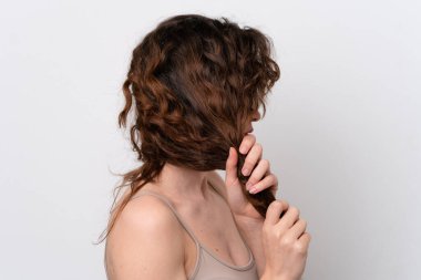 Beyaz arka planda izole edilmiş genç beyaz kadın saçlarına dokunuyor. Portreyi kapat