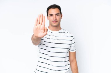 Beyaz arka planda izole edilmiş genç beyaz adam dur hareketi yapıyor.