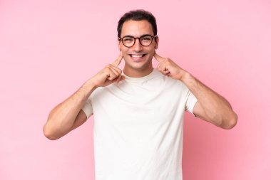 Young caucasian man isolated on pink background smiling with a happy and pleasant expression