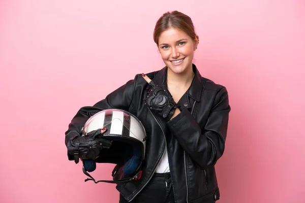 Young caucasian woman with a motorcycle helmet isolated on pink background pointing to the side to present a product