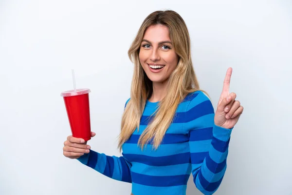 Young Uruguayan woman drinking soda isolated on white background showing and lifting a finger in sign of the best