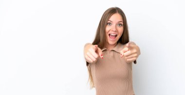 Beyaz arka planda izole edilmiş genç Litvanyalı kadın şaşırmış ve ön tarafı işaret ediyor.