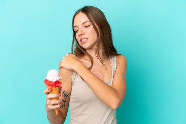 Young Lithuanian woman with cornet ice cream isolated on blue background suffering from pain in shoulder for having made an effort