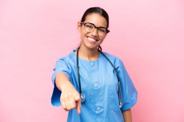Young nurse Colombian woman isolated on pink background points finger at you with a confident expression
