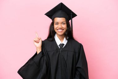 Young university Colombian woman graduate isolated on pink background showing and lifting a finger in sign of the best