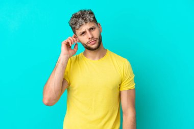 Mavi arka planda izole edilmiş yakışıklı beyaz adam kuşkuları var.