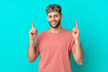 Mavi arka planda izole edilmiş yakışıklı beyaz adam harika bir fikre işaret ediyor.