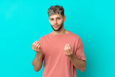 Genç yakışıklı beyaz adam mavi arka planda izole edilmiş para hareketi yapıyor ama mahvoldu.