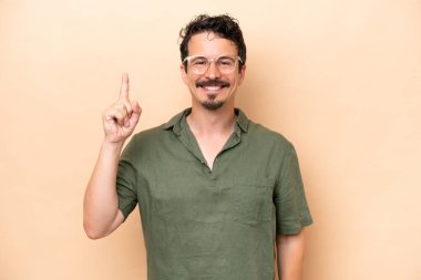Beyazların arka planında izole edilmiş genç beyaz adam harika bir fikre işaret ediyor.