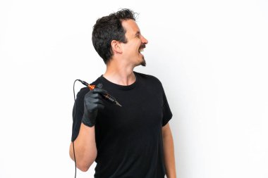 Dövme sanatçısı beyaz arka planda izole edilmiş. Yan pozisyonda gülüyor.