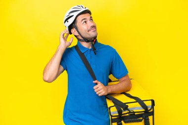 Young handsome man with thermal backpack over isolated yellow background thinking an idea