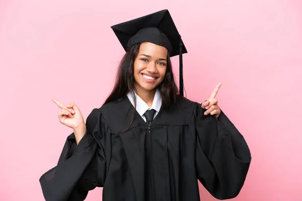 Young university Colombian woman graduate isolated on pink background pointing finger to the laterals and happy