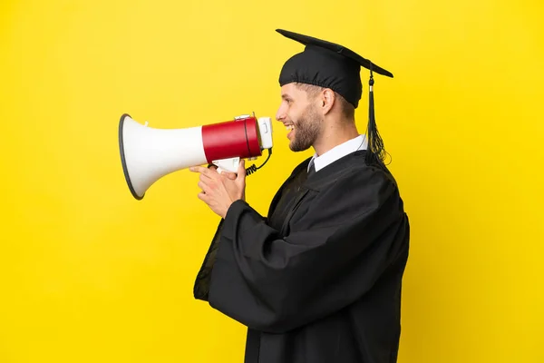 stock image Young university graduate caucasian man isolated on yellow background shouting through a megaphone