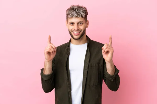 Νεαρός Όμορφος Καυκάσιος Άντρας Απομονωμένος Ροζ Φόντο Δείχνοντας Μια Σπουδαία — Φωτογραφία Αρχείου