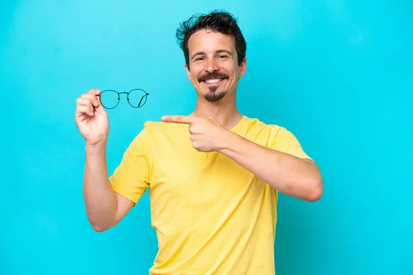 Young Caucasian Man Holding Glasses Isolated Blue Background Pointing — Stock Photo, Image