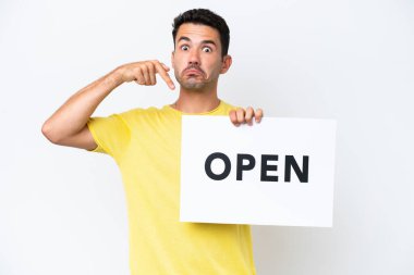İzole edilmiş beyaz arka planda genç yakışıklı bir adam elinde açık yazılı bir pankart tutuyor ve onu işaret ediyor.