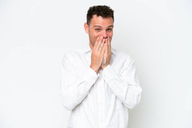 Beyaz arka planda izole edilmiş beyaz tenli yakışıklı adam mutlu ve gülümseyen elleriyle ağzını kapatıyor.