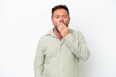 Beyaz arka planda izole edilmiş orta yaşlı beyaz bir adam esniyor ve ağzını eliyle kapatıyor.