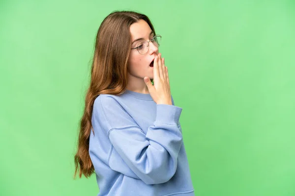 Teenager girl over isolated chroma key background yawning and covering wide open mouth with hand