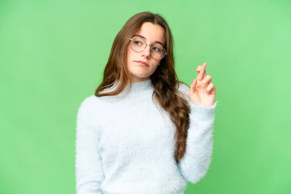 Teenager girl over isolated chroma key background with fingers crossing and wishing the best