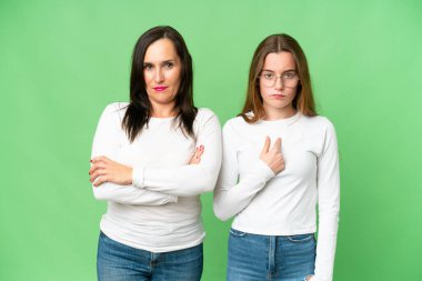 mother and daughter over isolated chroma key background annoyed angry in furious gesture