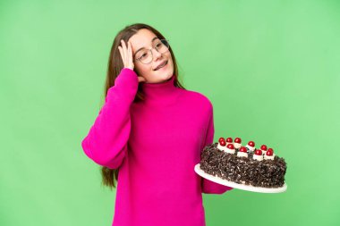 Teenager girl holding birthday cake over isolated chroma key background smiling a lot