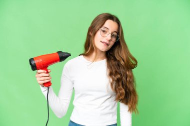 Teenager girl holding a hairdryer over isolated chroma key background smiling a lot