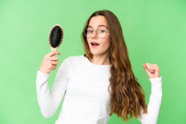 Teenager girl with hair comb over isolated chroma key background celebrating a victory