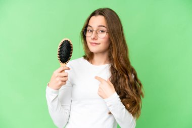 Teenager girl with hair comb over isolated chroma key background with surprise facial expression