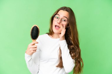 Teenager girl with hair comb over isolated chroma key background shouting with mouth wide open