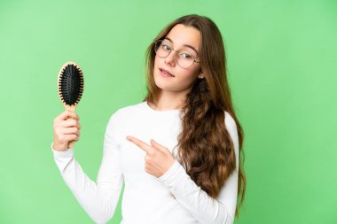 Teenager girl with hair comb over isolated chroma key background and pointing it