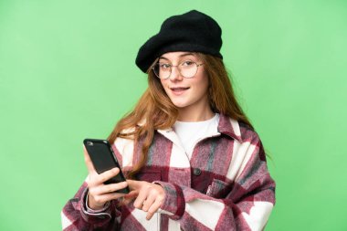 Teenager girl over isolated chroma key background sending a message or email with the mobile