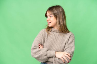 İzole edilmiş krom anahtar geçmişi olan genç bir kız yana bakıyor ve gülümsüyor.