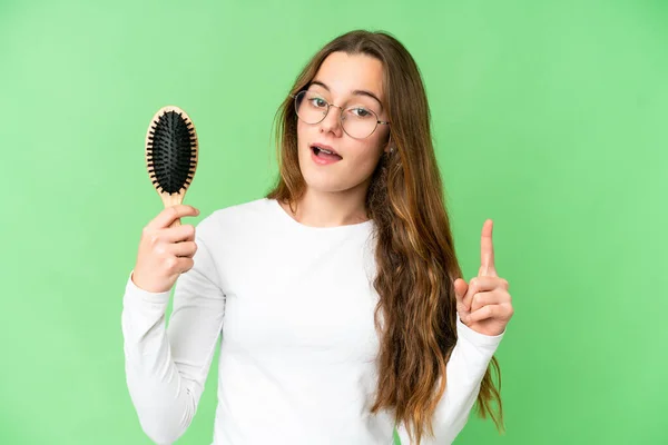 Teenager girl with hair comb over isolated chroma key background pointing up a great idea