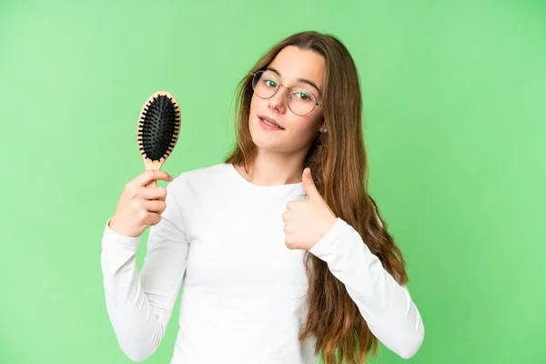 Teenager girl with hair comb over isolated chroma key background with thumbs up because something good has happened