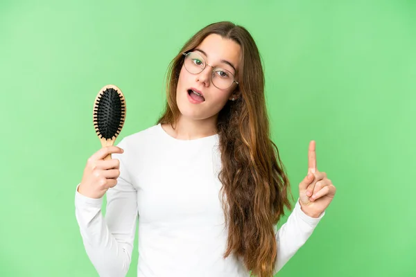 Teenager girl with hair comb over isolated chroma key background intending to realizes the solution while lifting a finger up