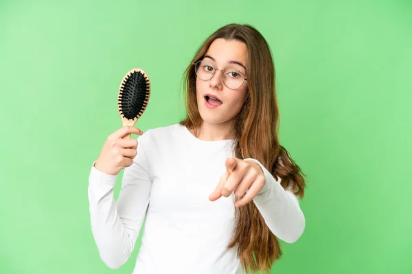 Teenager girl with hair comb over isolated chroma key background surprised and pointing front