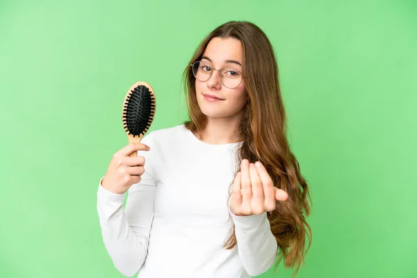 Teenager girl with hair comb over isolated chroma key background inviting to come with hand. Happy that you came