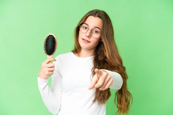 Teenager girl with hair comb over isolated chroma key background points finger at you with a confident expression